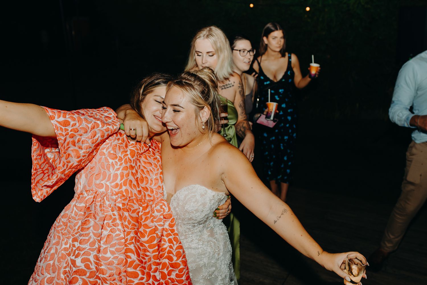 Dancing guests enjoy a lively moment at an evening wedding reception celebration.