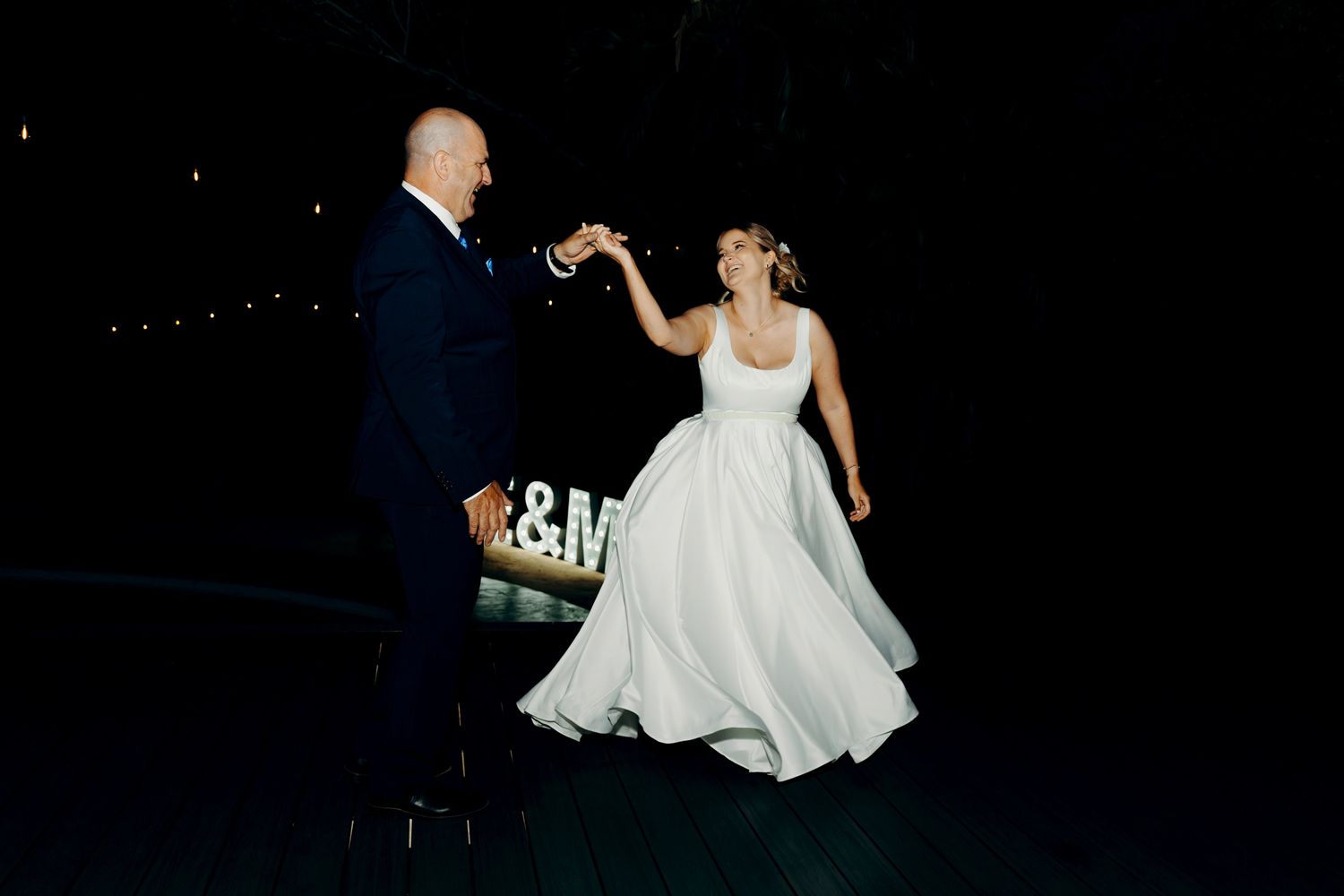 A couple shares a romantic dance moment under the night sky at their wedding reception.