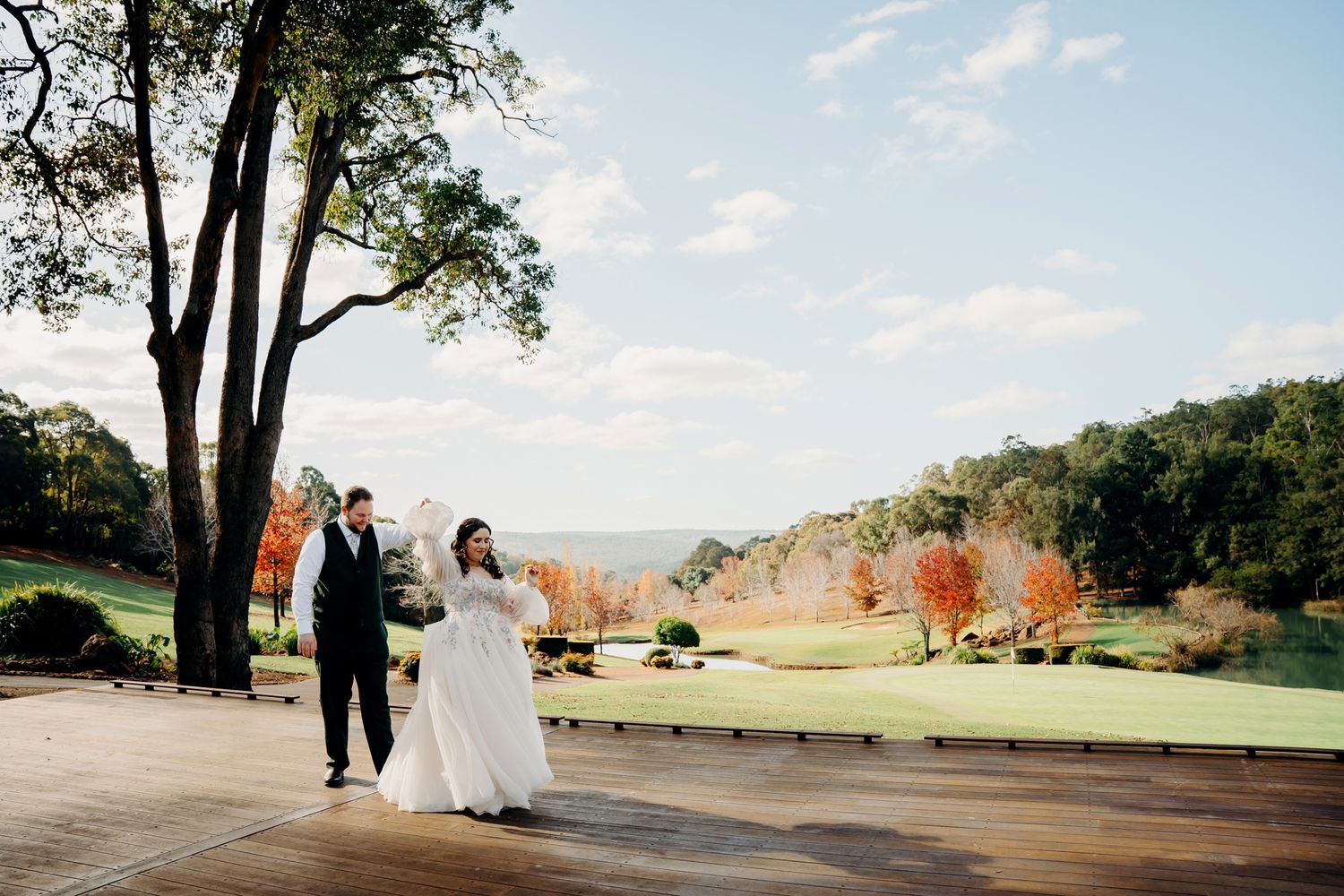 A scenic autumn wedding on a hilltop golf course with vibrant fall colors and lush trees in the background.