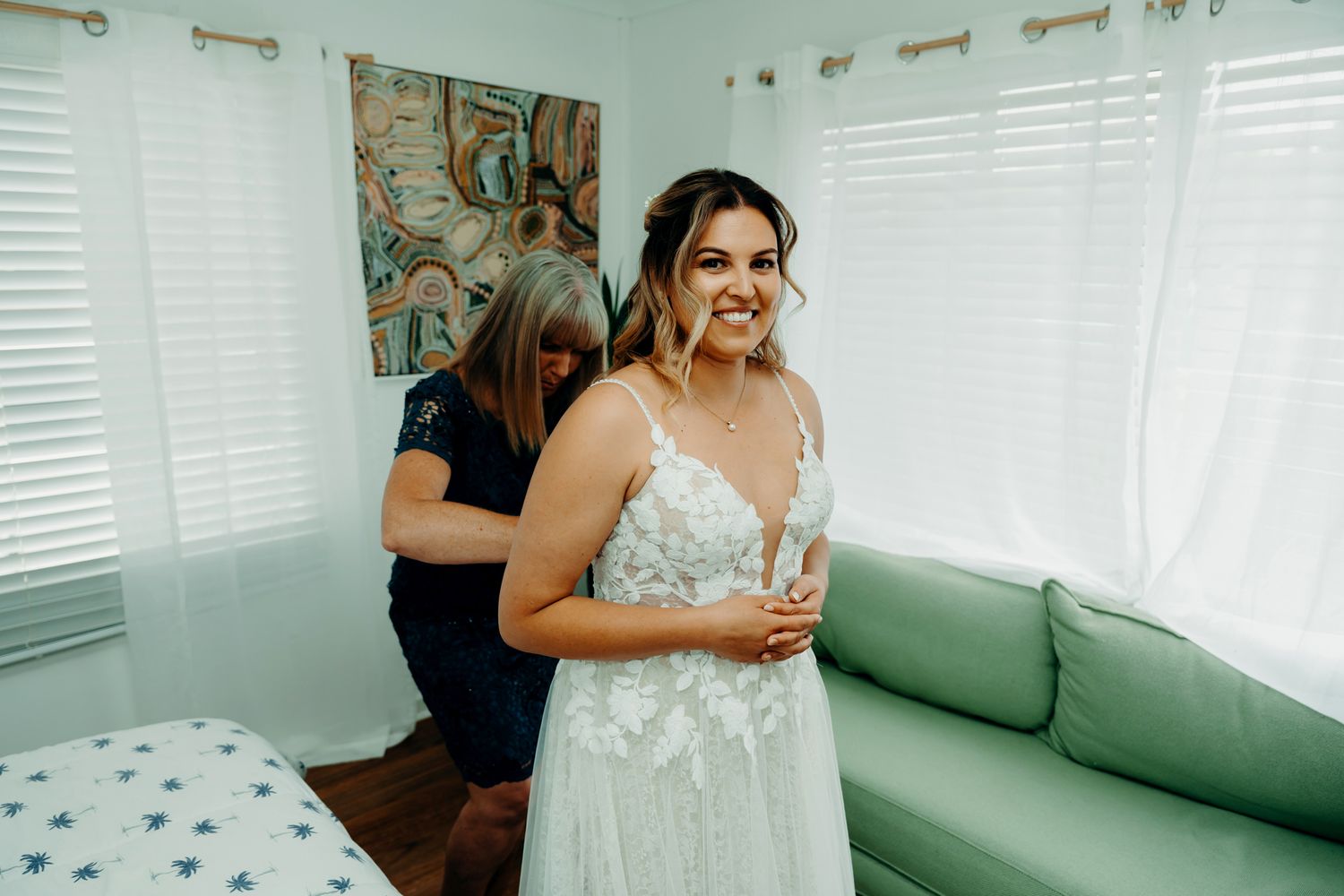 A joyful wedding scene shows a group celebrating on a mint green couch in a bright sunlit room.