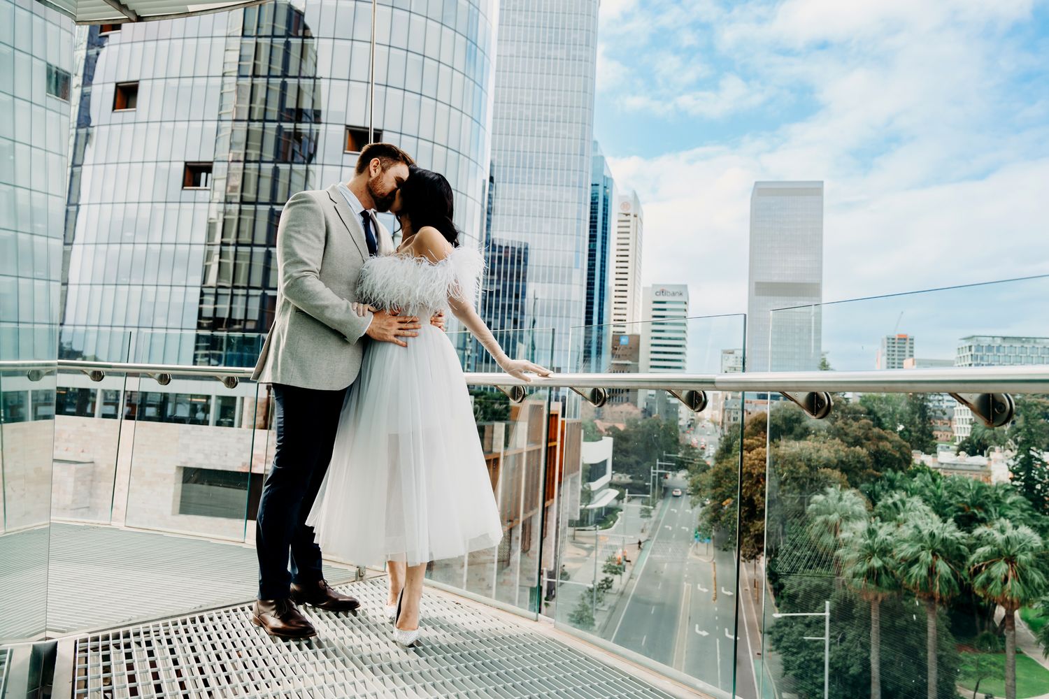 Romantic rooftop wedding portrait with modern city skyline and architecture in background.