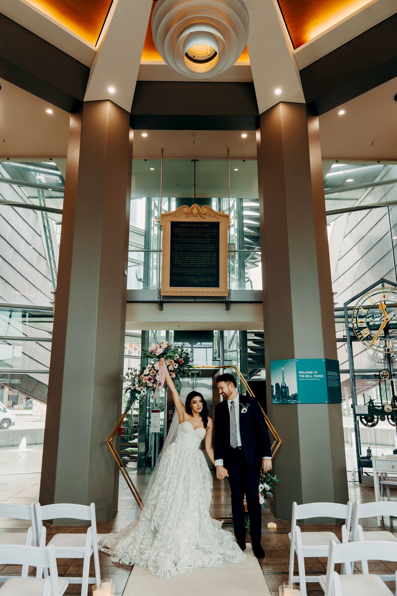Modern wedding venue with dramatic architectural lighting and white chairs set up for ceremony.