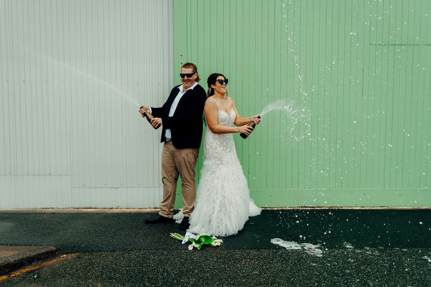 Wedding couple embracing against a mint green wall in an artistic composition.