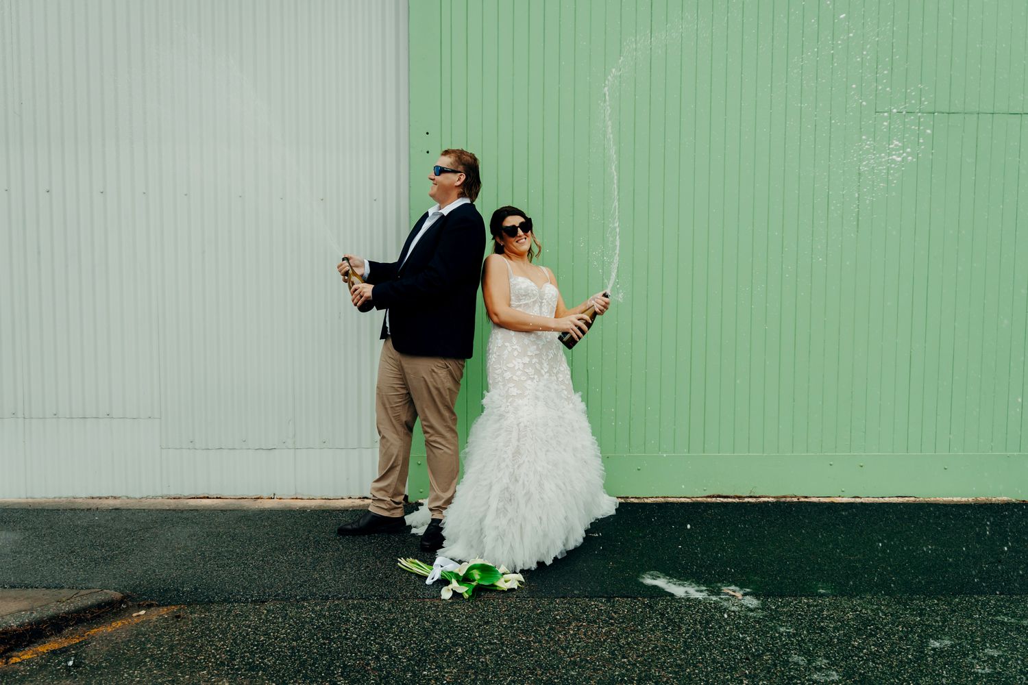 Wedding couple poses against mint green wall in creative wedding day portraits.