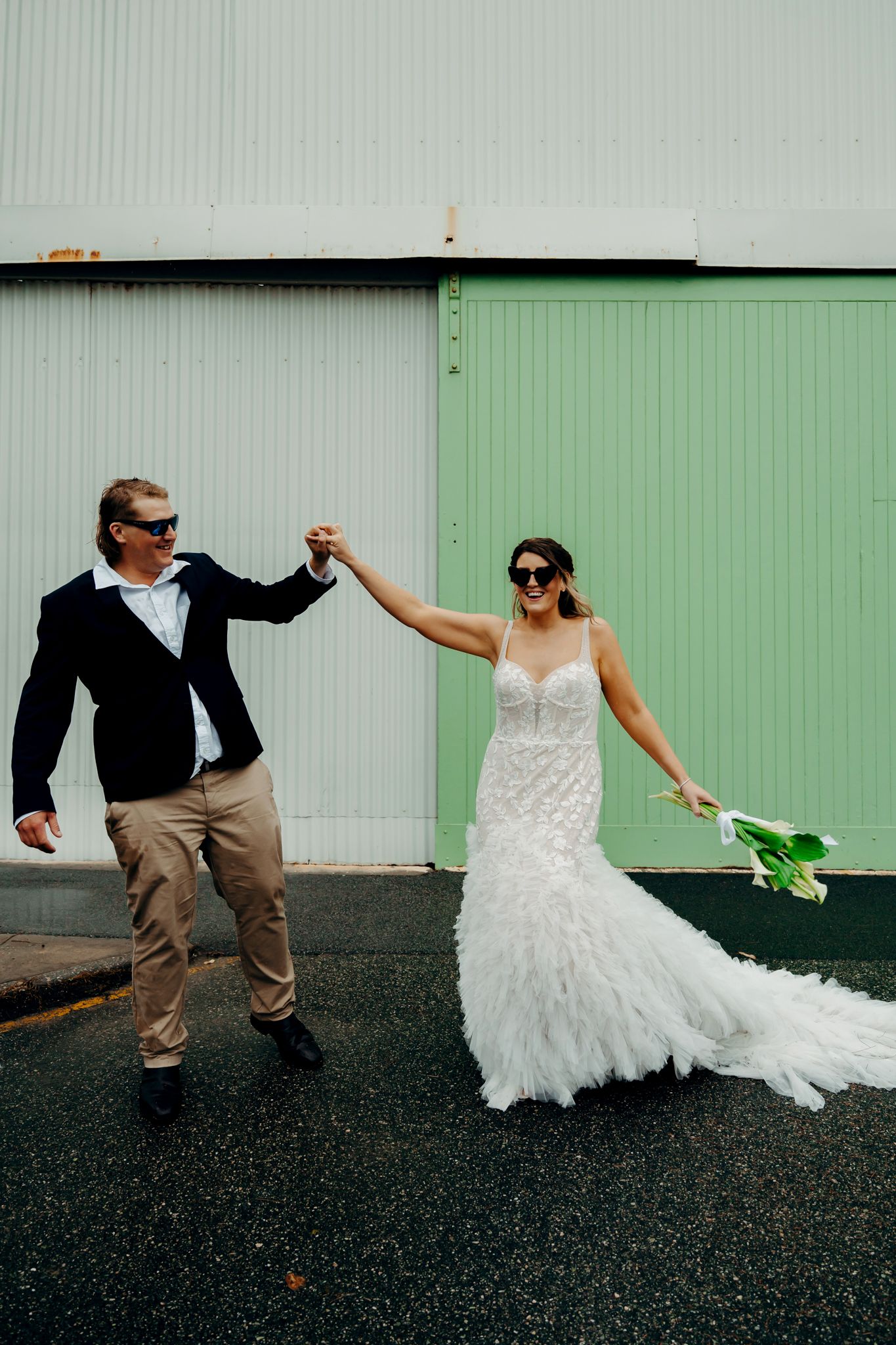 A fun wedding photo shows a couple in sunglasses dancing together against a mint green wall.