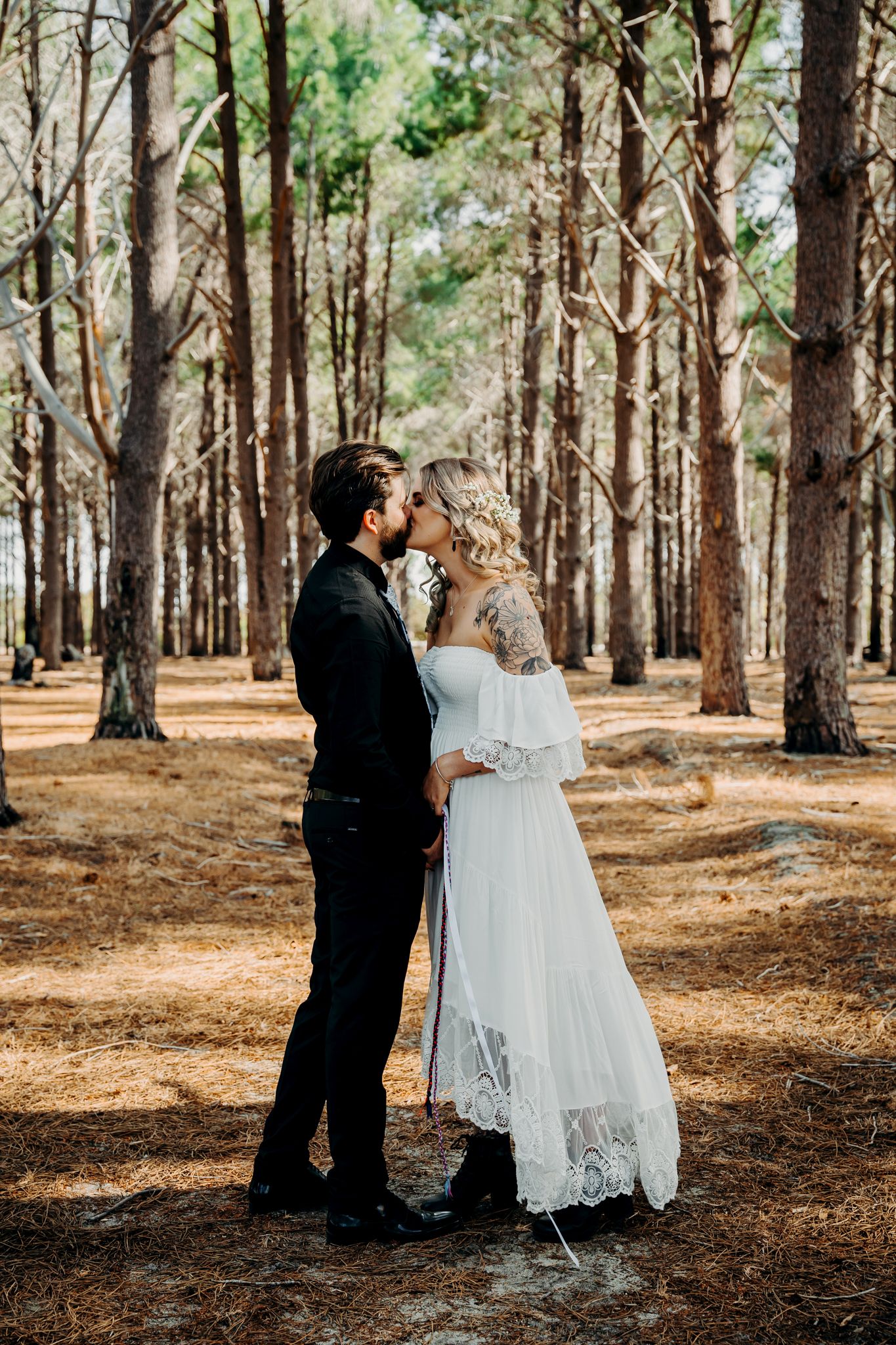 Romantic wedding portrait of couple embracing in pine forest.
