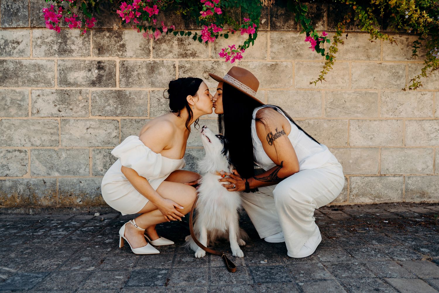 A sequence of romantic wedding photographs captured in front of a rustic stone wall with vibrant pink flowers.