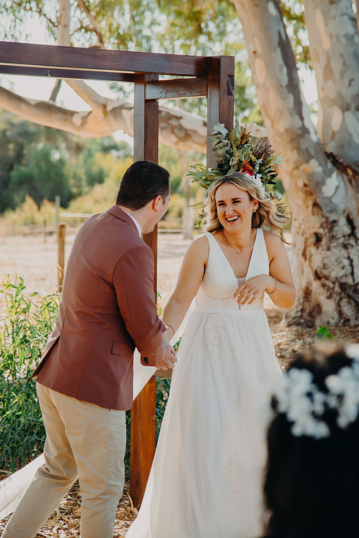 Joyful moment captured during outdoor wedding ceremony under eucalyptus trees.