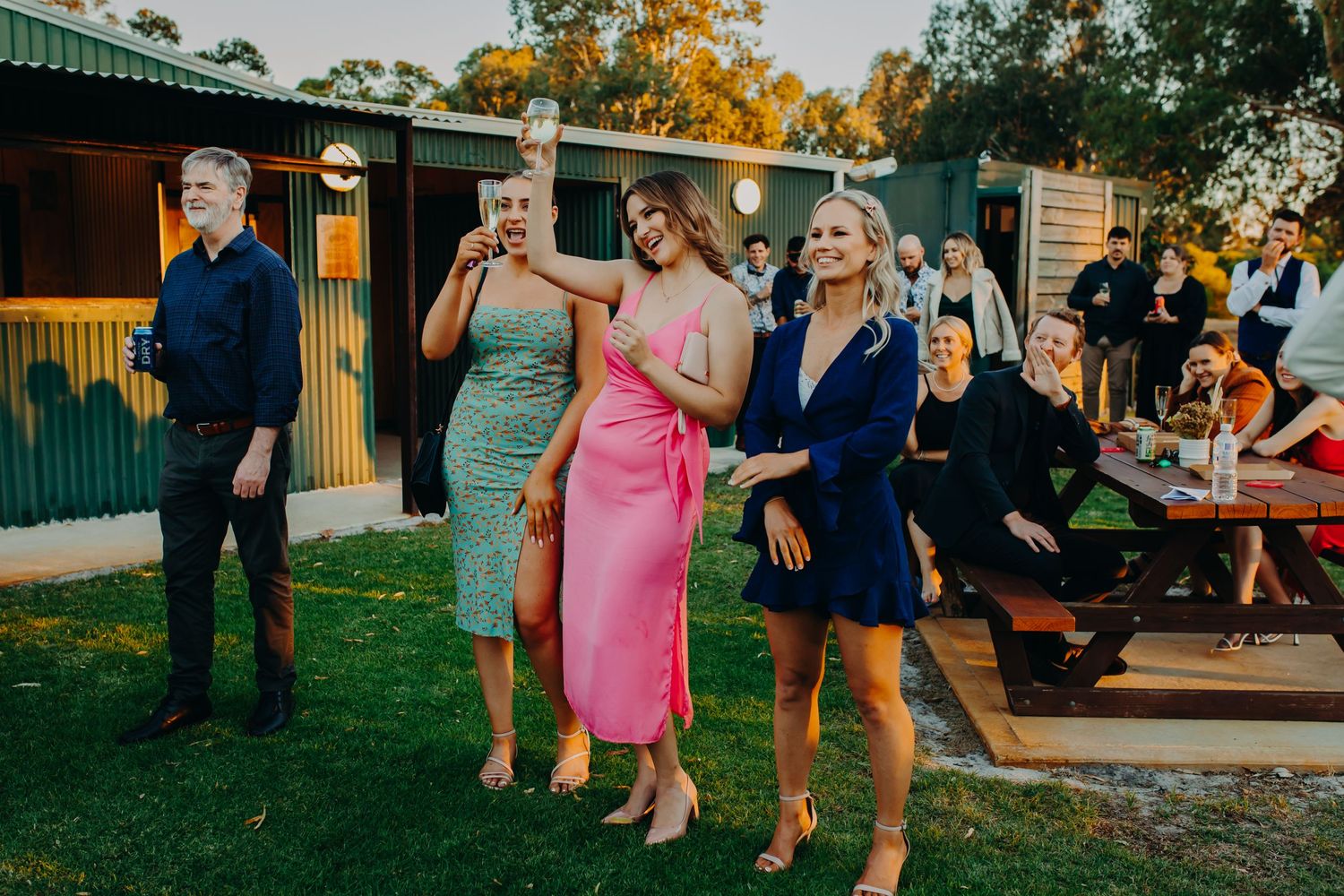 Wedding guests in colorful dresses enjoying an outdoor reception.