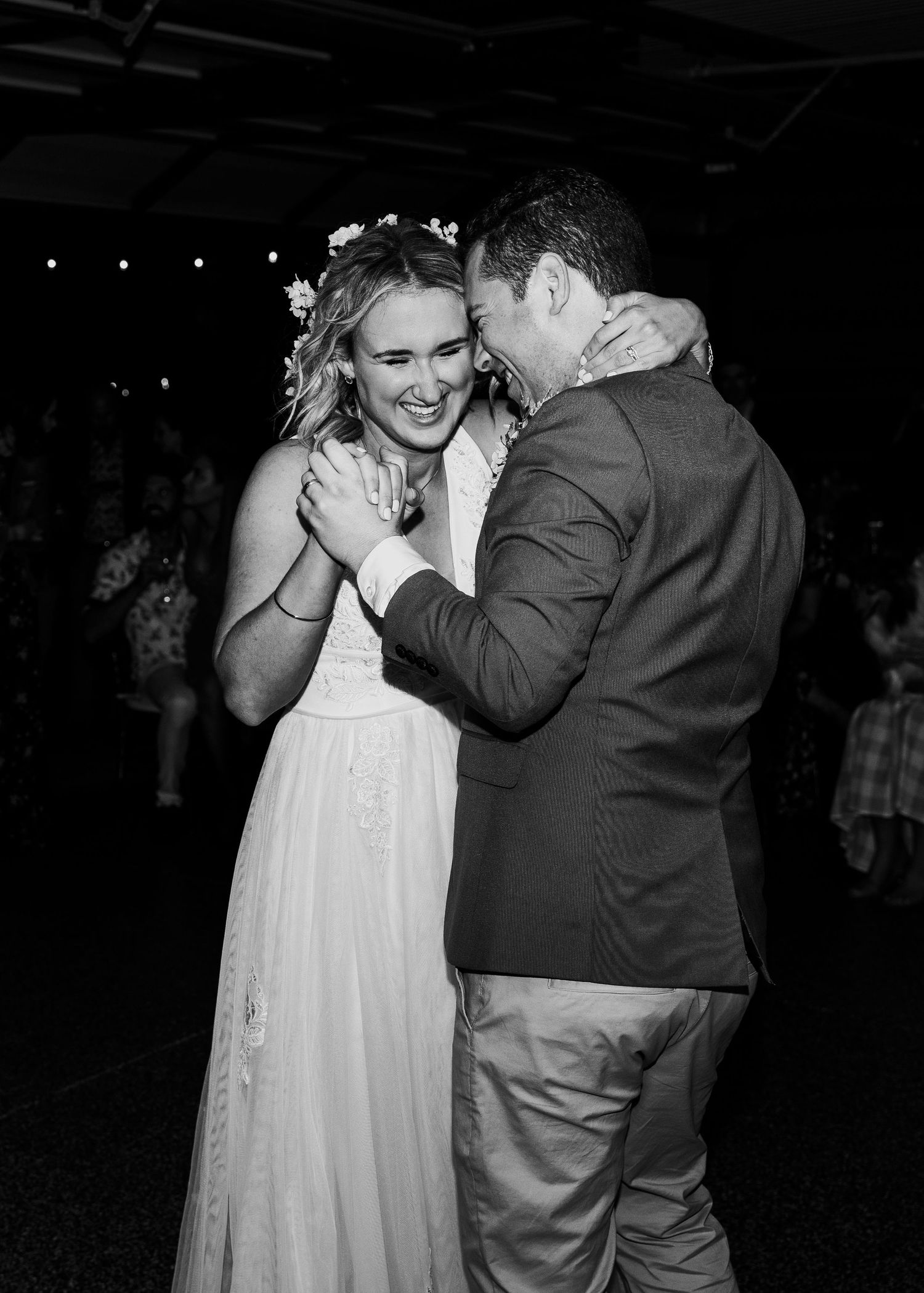 A romantic black and white photo of a bride and groom sharing an intimate dance moment at their wedding reception.