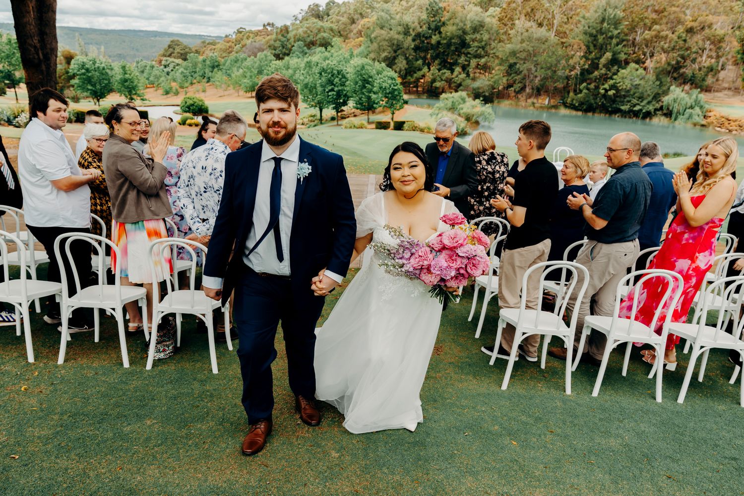 Outdoor wedding ceremony setup with white chairs arranged on a grassy lawn facing scenic mountain views.
