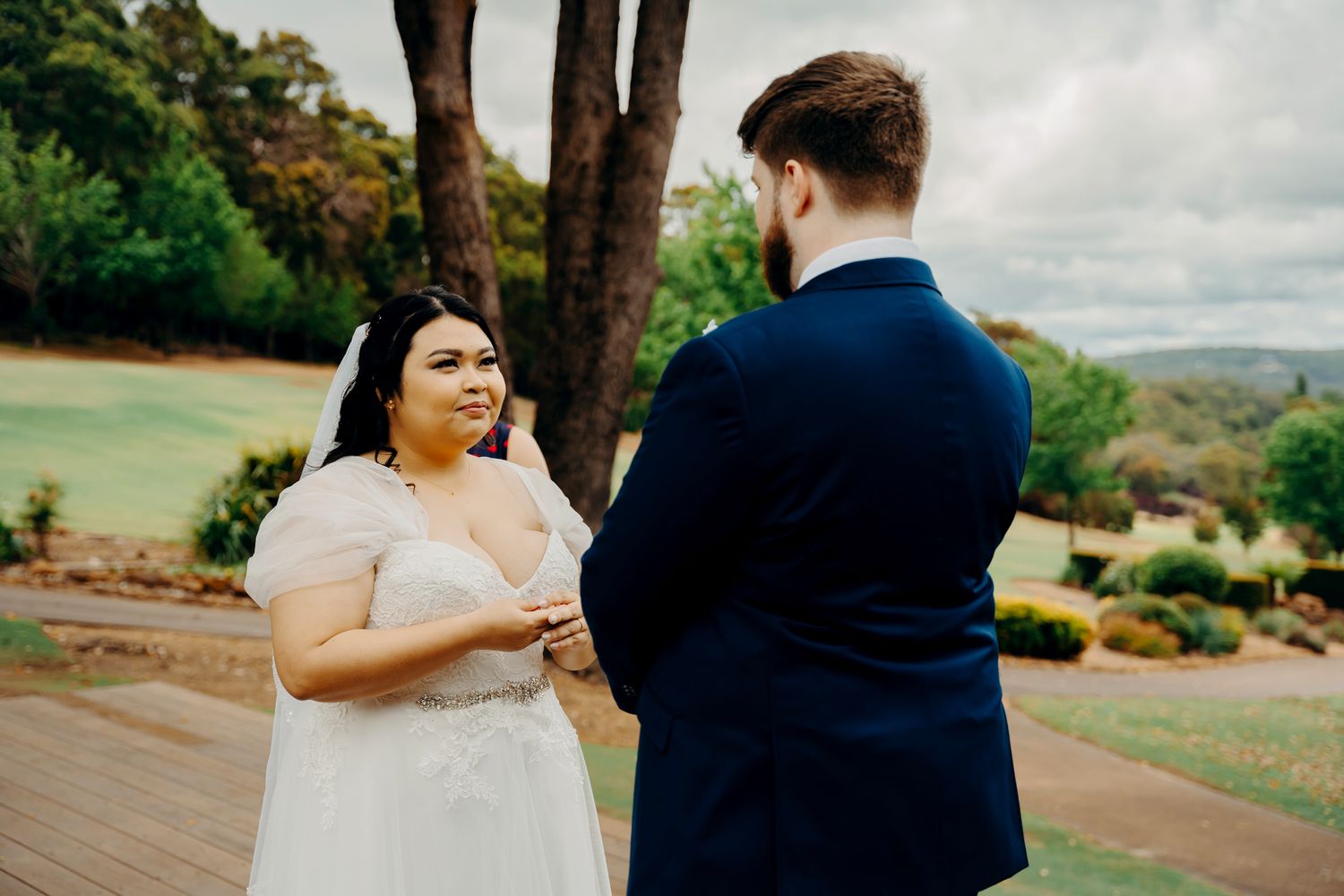 Couple exchanges vows during an intimate outdoor ceremony against a scenic landscape backdrop.