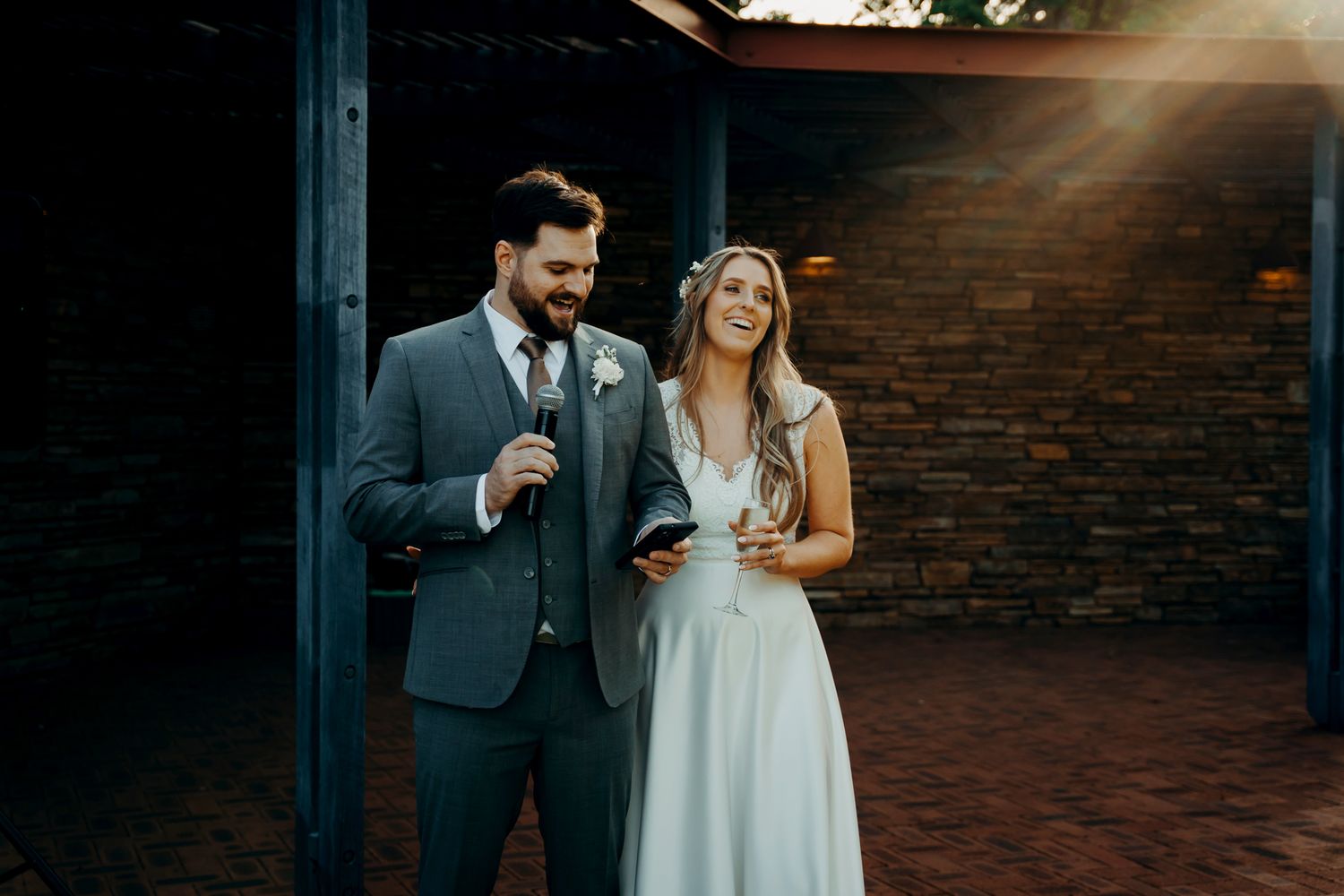 A couple shares a romantic moment during sunset at a rustic brick venue.