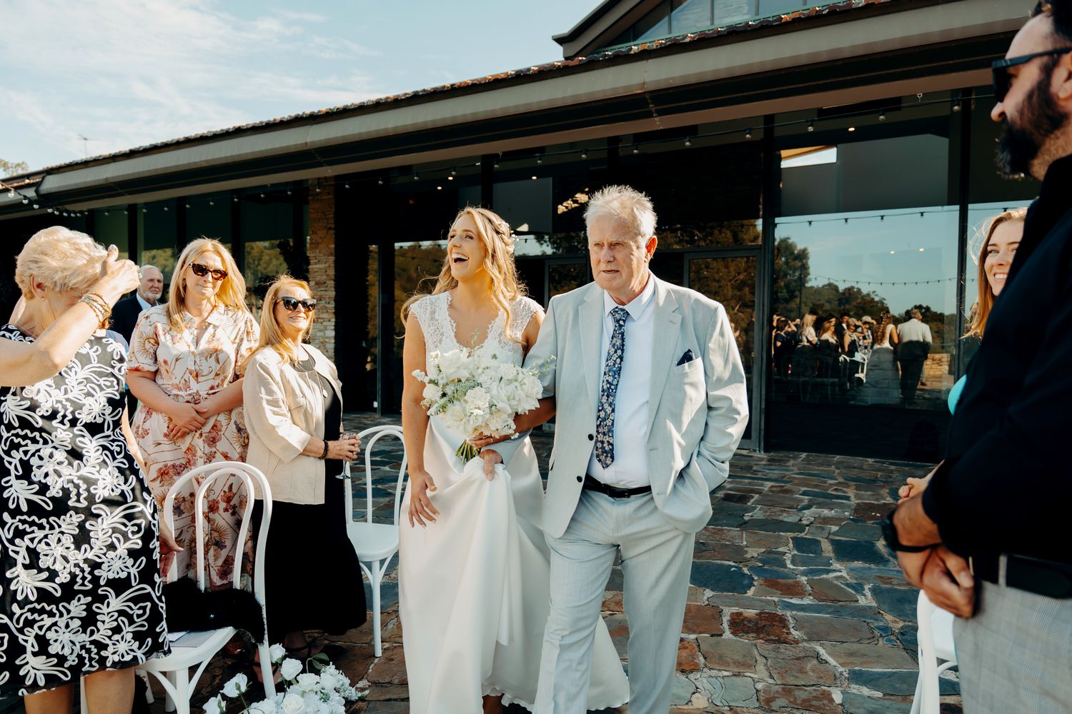Wedding party celebrates and dances together during an outdoor reception at sunset.
