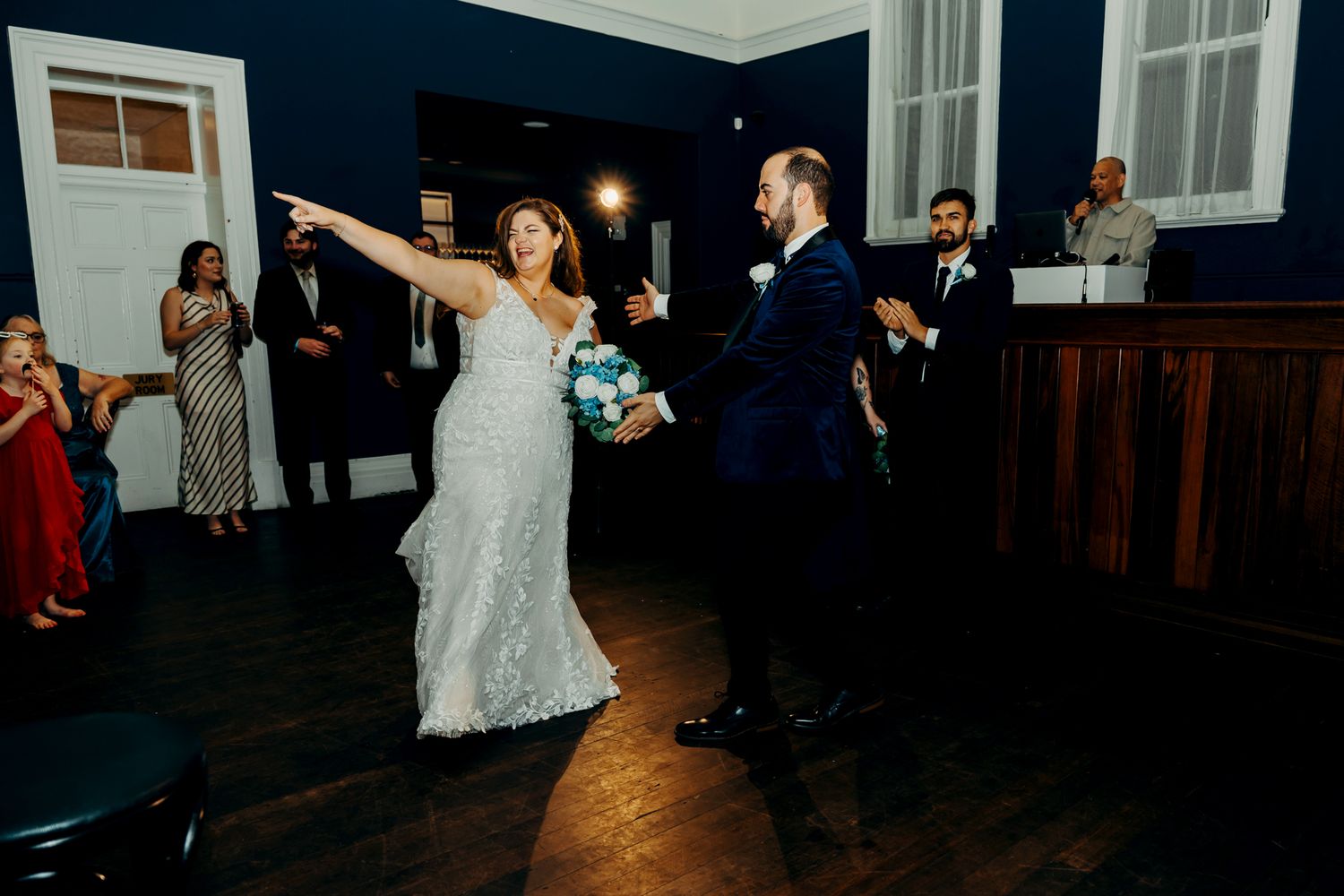 Newlyweds sharing their first dance in an elegant venue with navy blue walls and white trim.