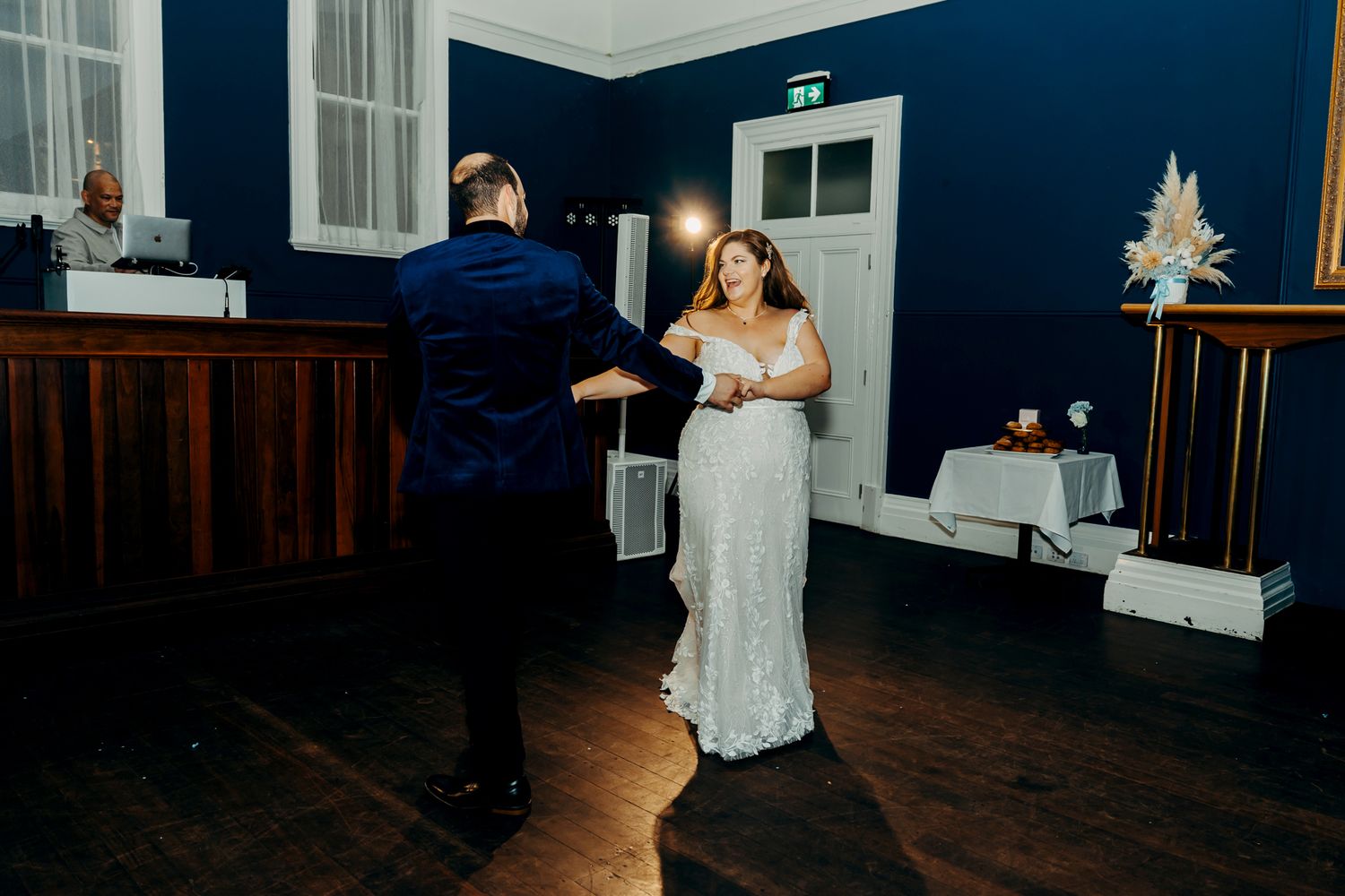 Wedding reception dance floor scene with guests celebrating in a blue-walled ballroom.