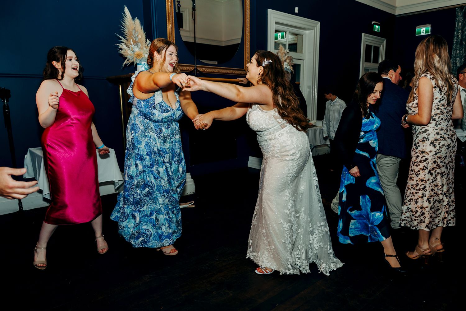 Wedding guests dancing and celebrating at a reception in formal attire.