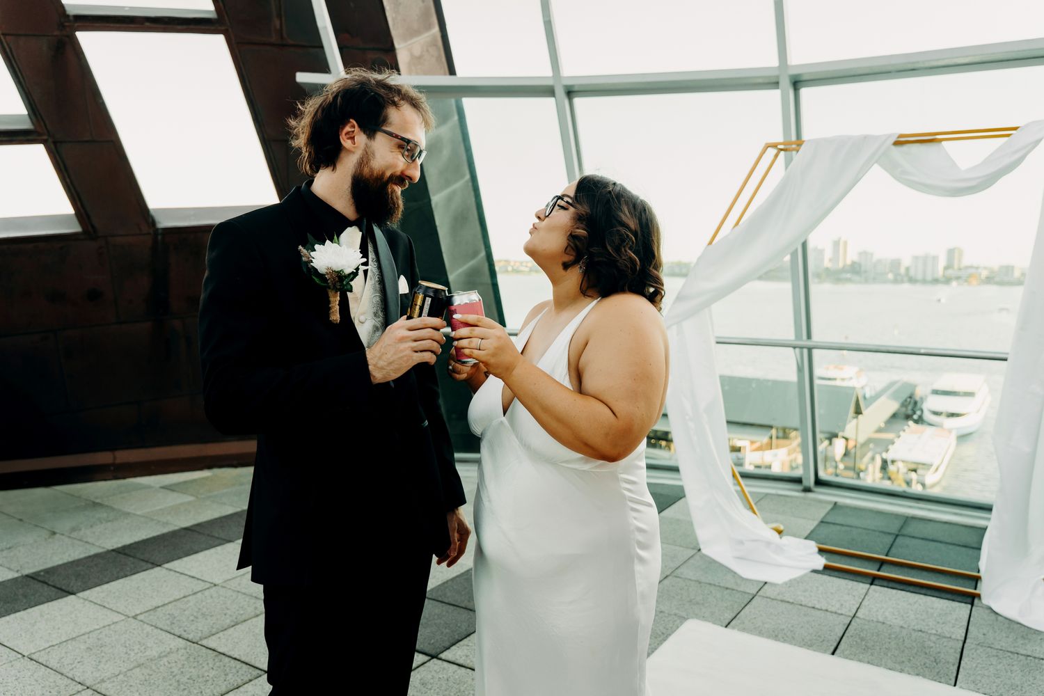 Silhouettes of a couple embrace in a modern space with large windows and natural light.