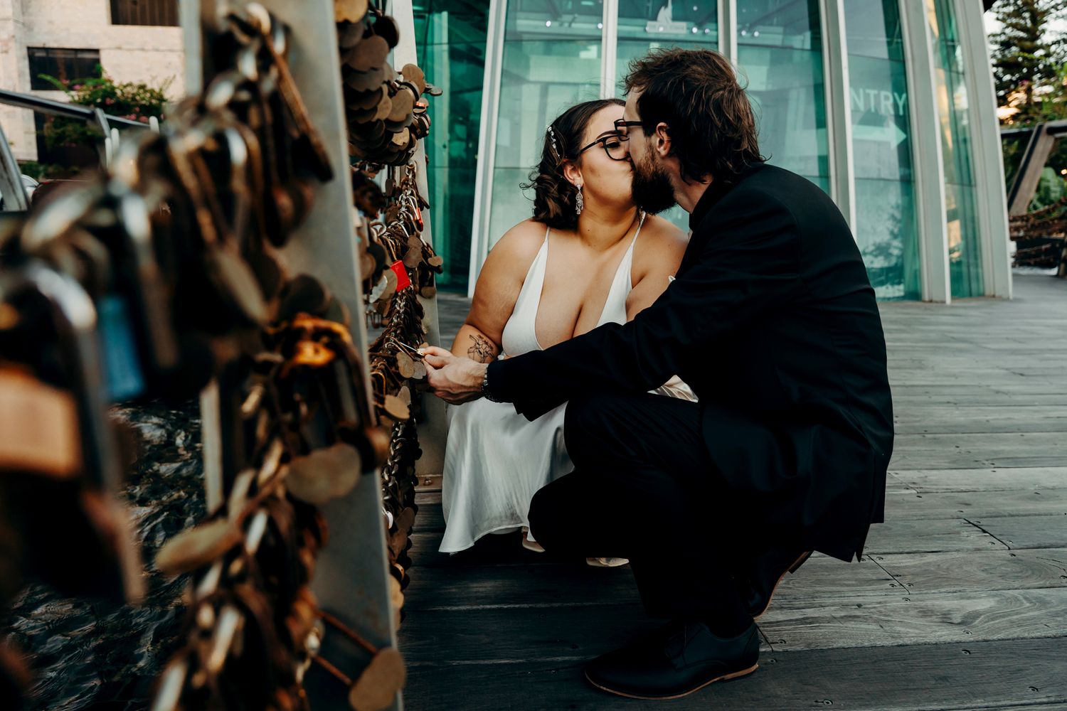 A romantic moment between a couple sharing an intimate embrace against a modern glass building exterior.