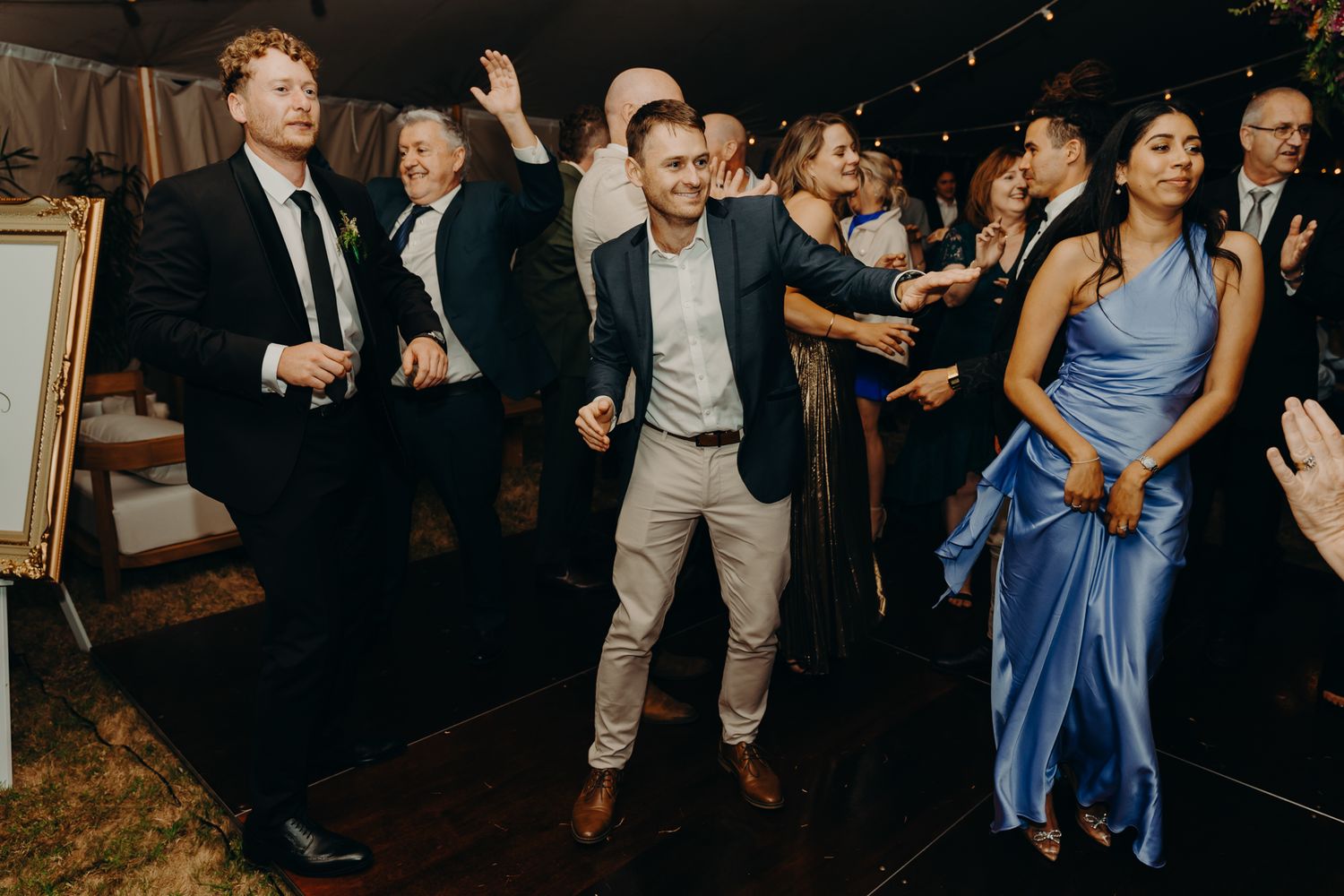 Energetic wedding reception with guests dancing under string lights.