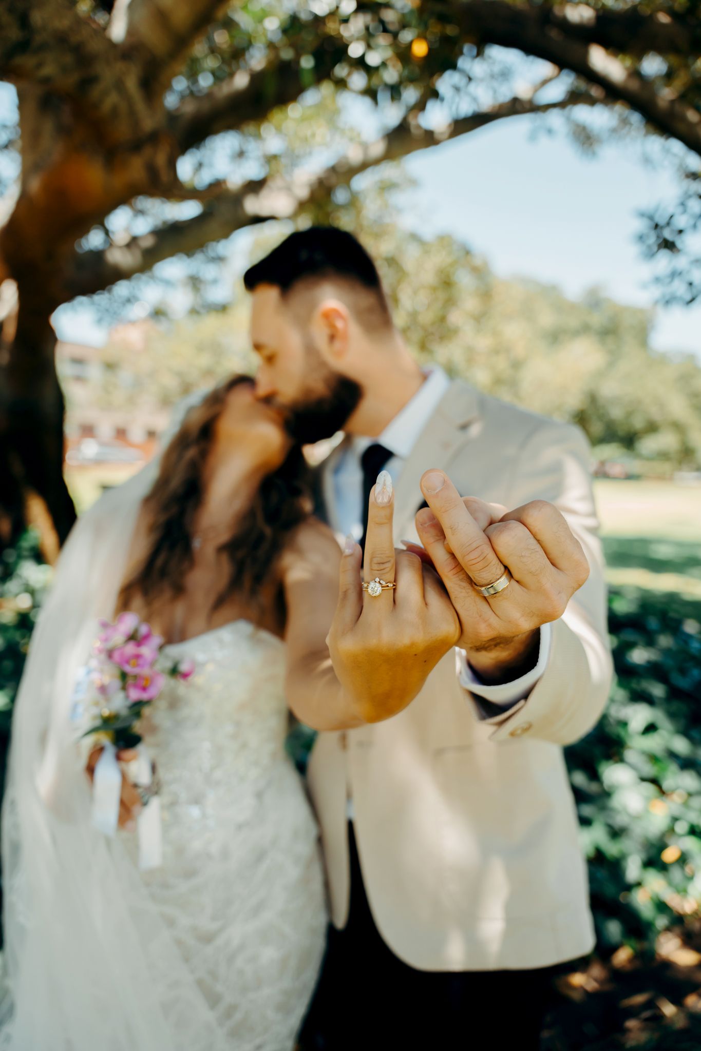 A series of romantic wedding photos showing close-up shots of hands with rings and tender embraces under sunlit trees.