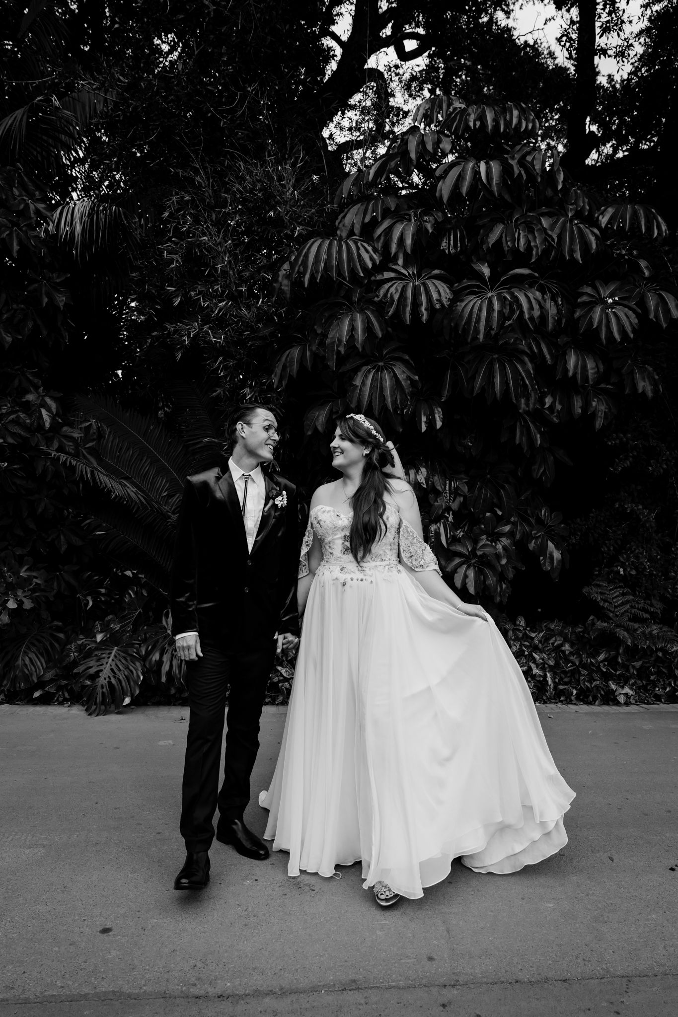 Black and white sequence showing a romantic stroll between a couple in wedding attire along a garden path.