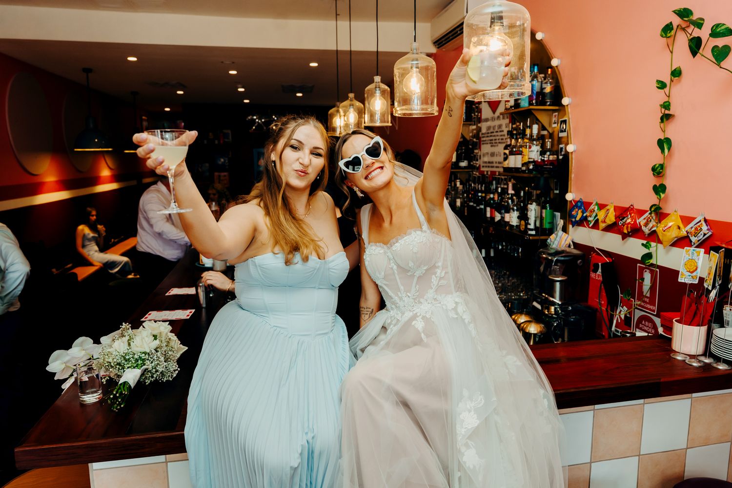 Wedding party members enjoy drinks and celebrate at a bar during wedding festivities.