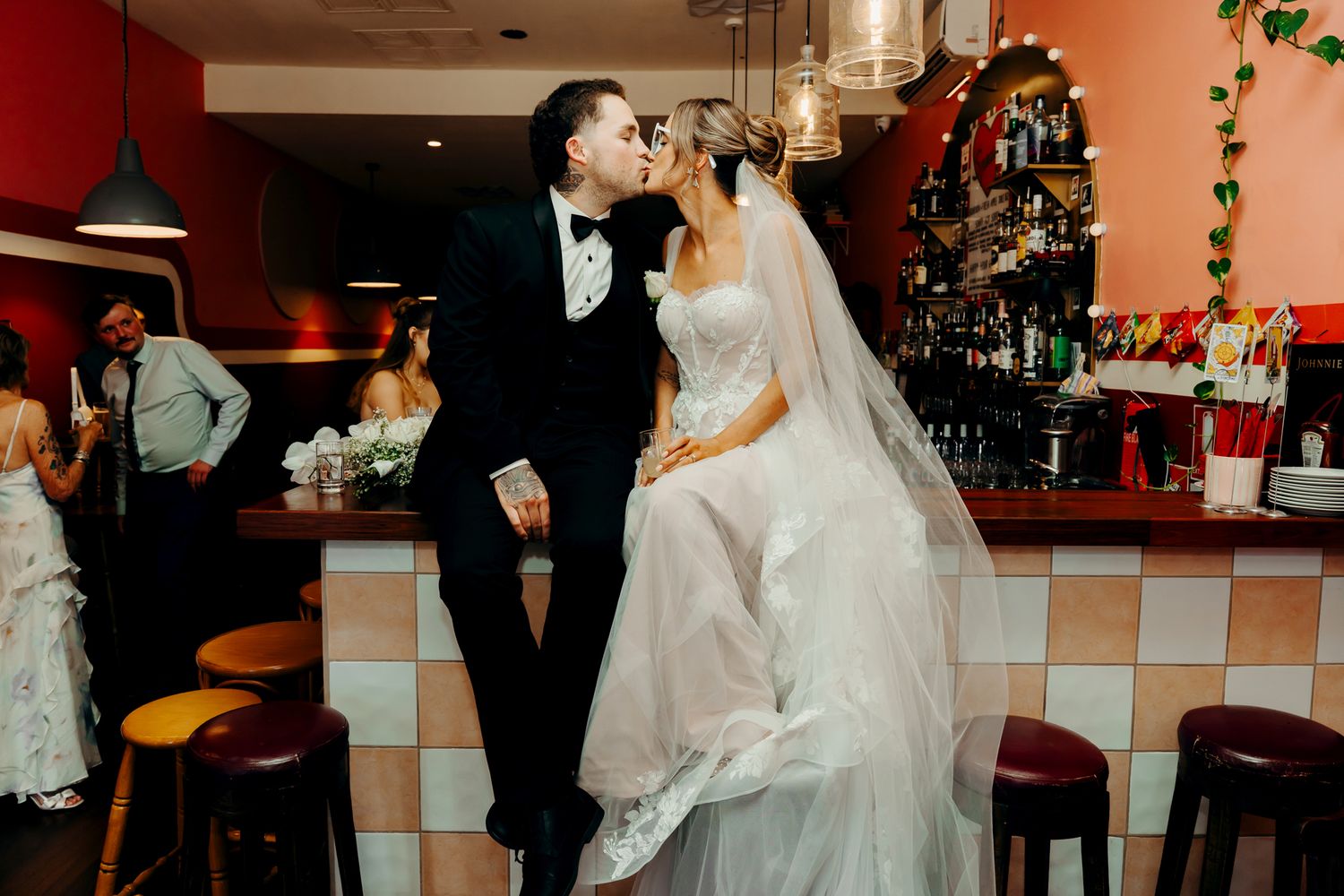 A series of romantic wedding moments captured at a bar or restaurant venue with warm lighting and red walls.