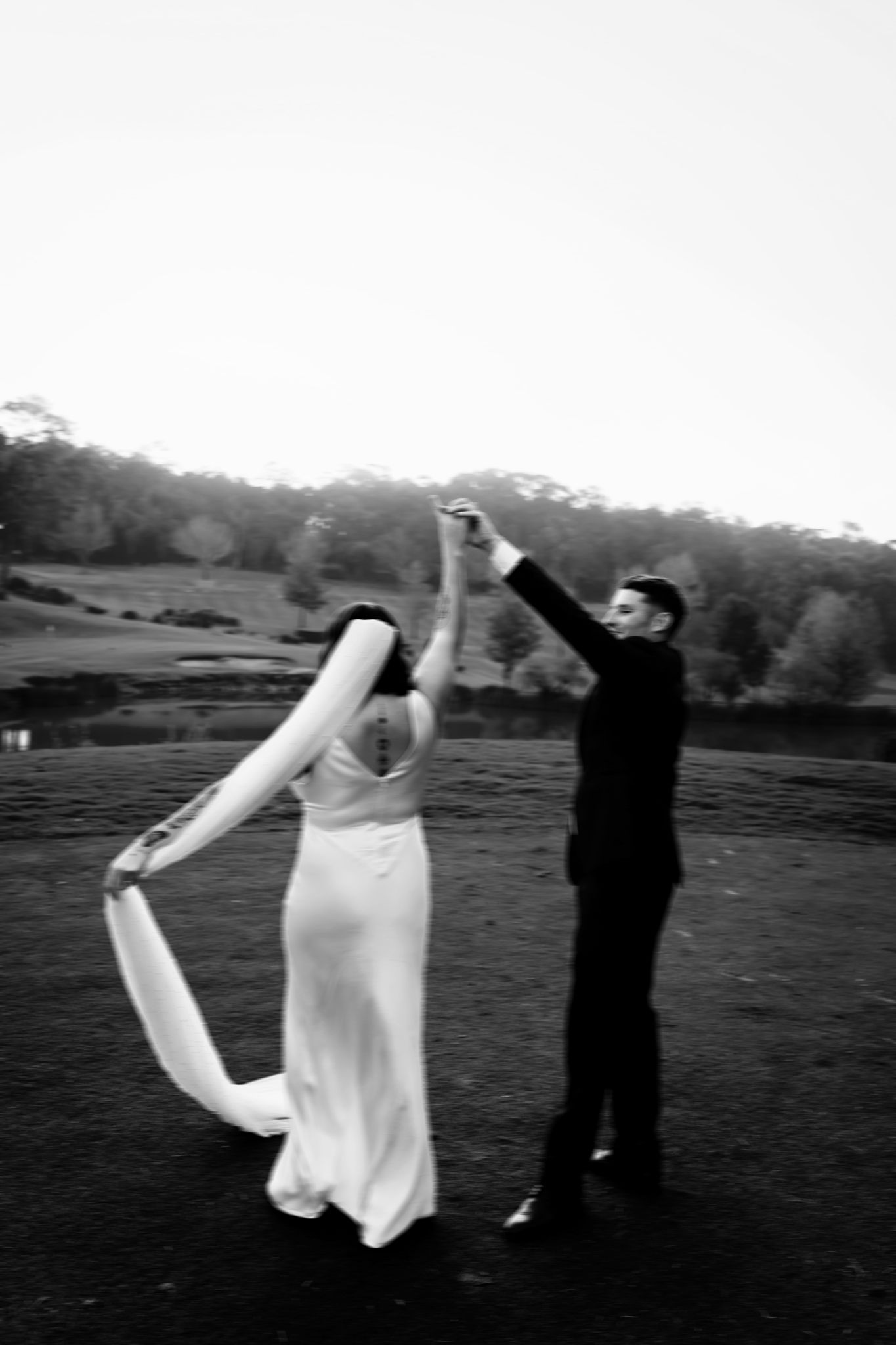 A sequence of black and white photos showing two figures in a field performing an ethereal dance or movement piece.