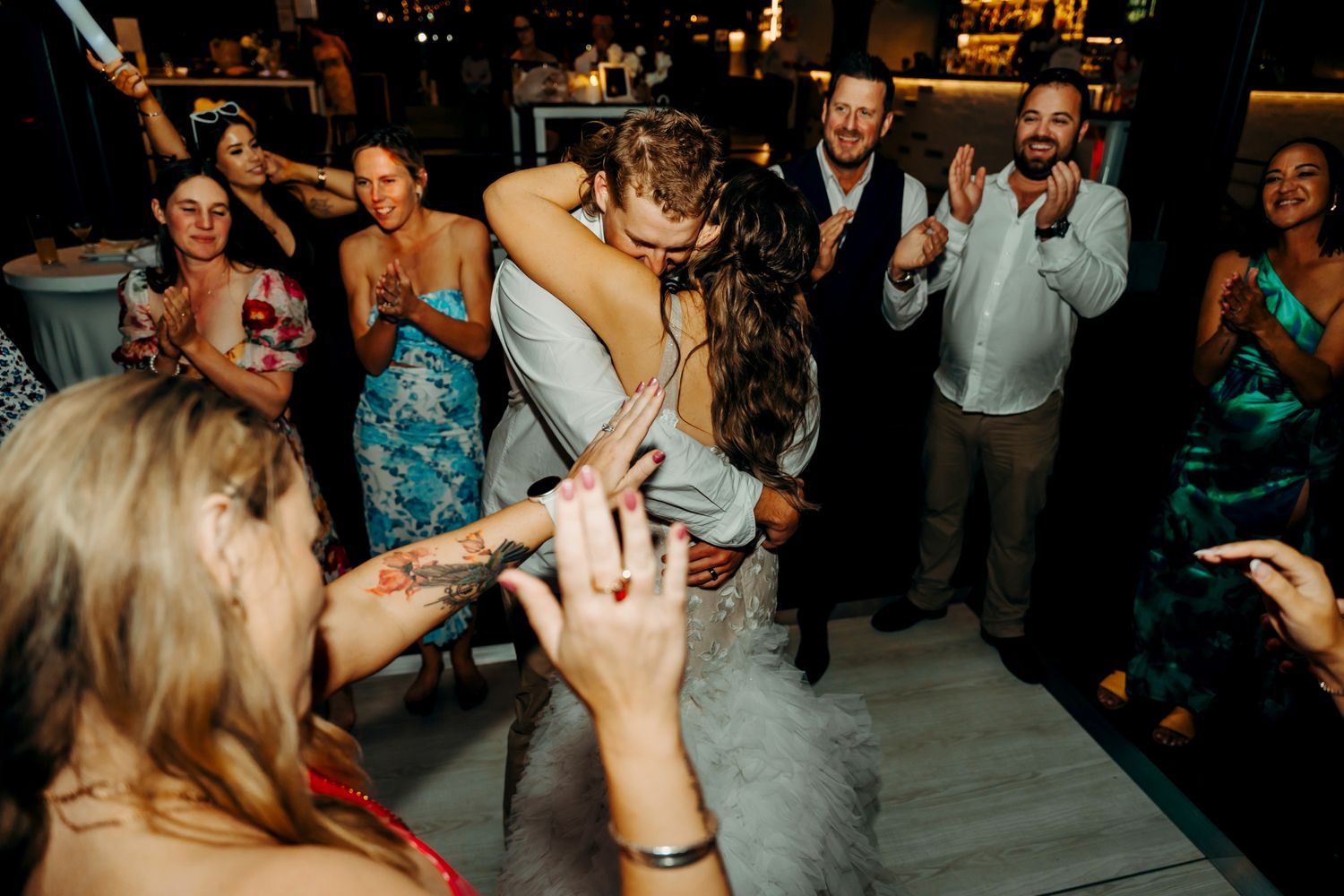 Wedding reception guests dancing energetically on a crowded dance floor at night.