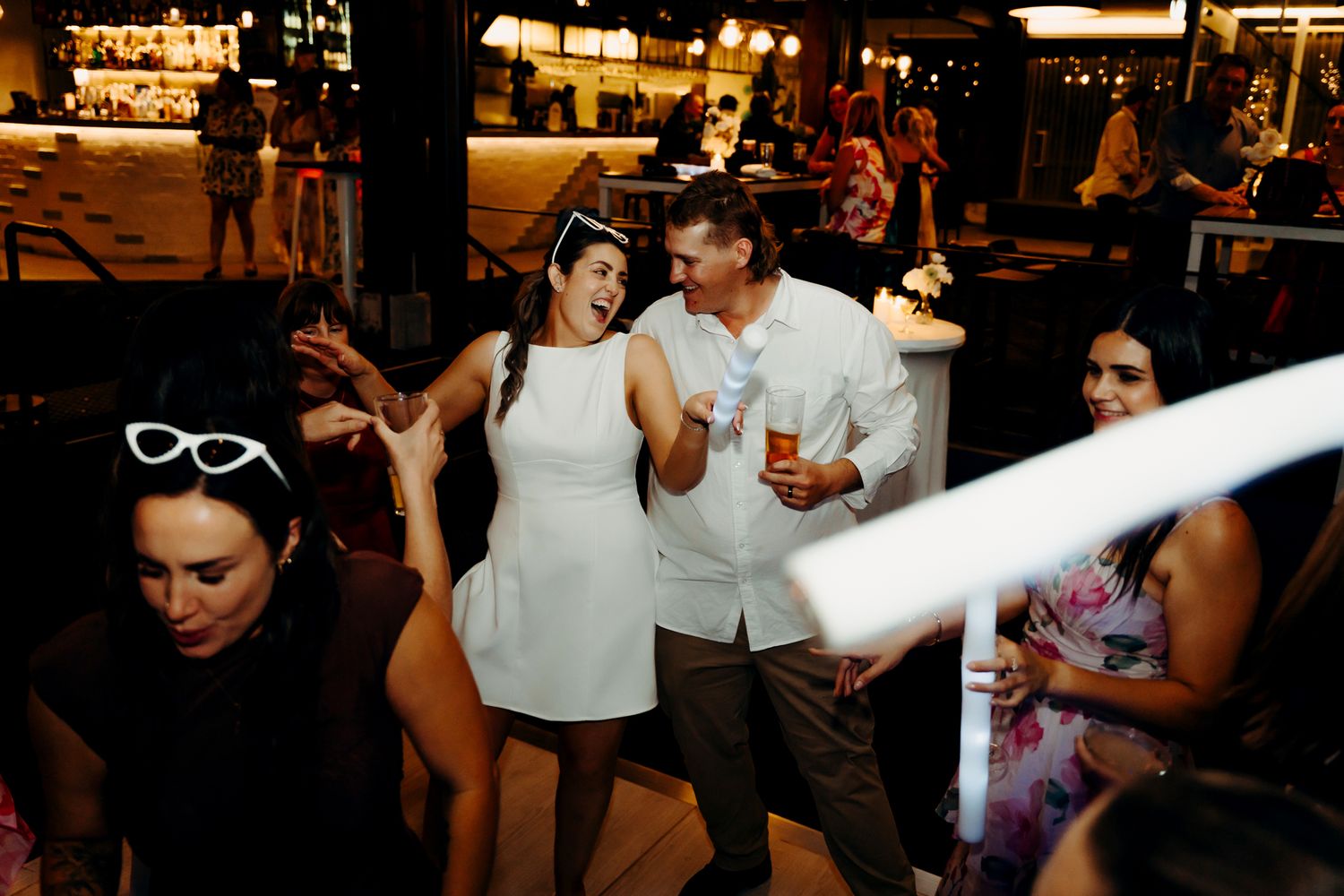 Wedding party dancing and celebrating under indoor lighting.