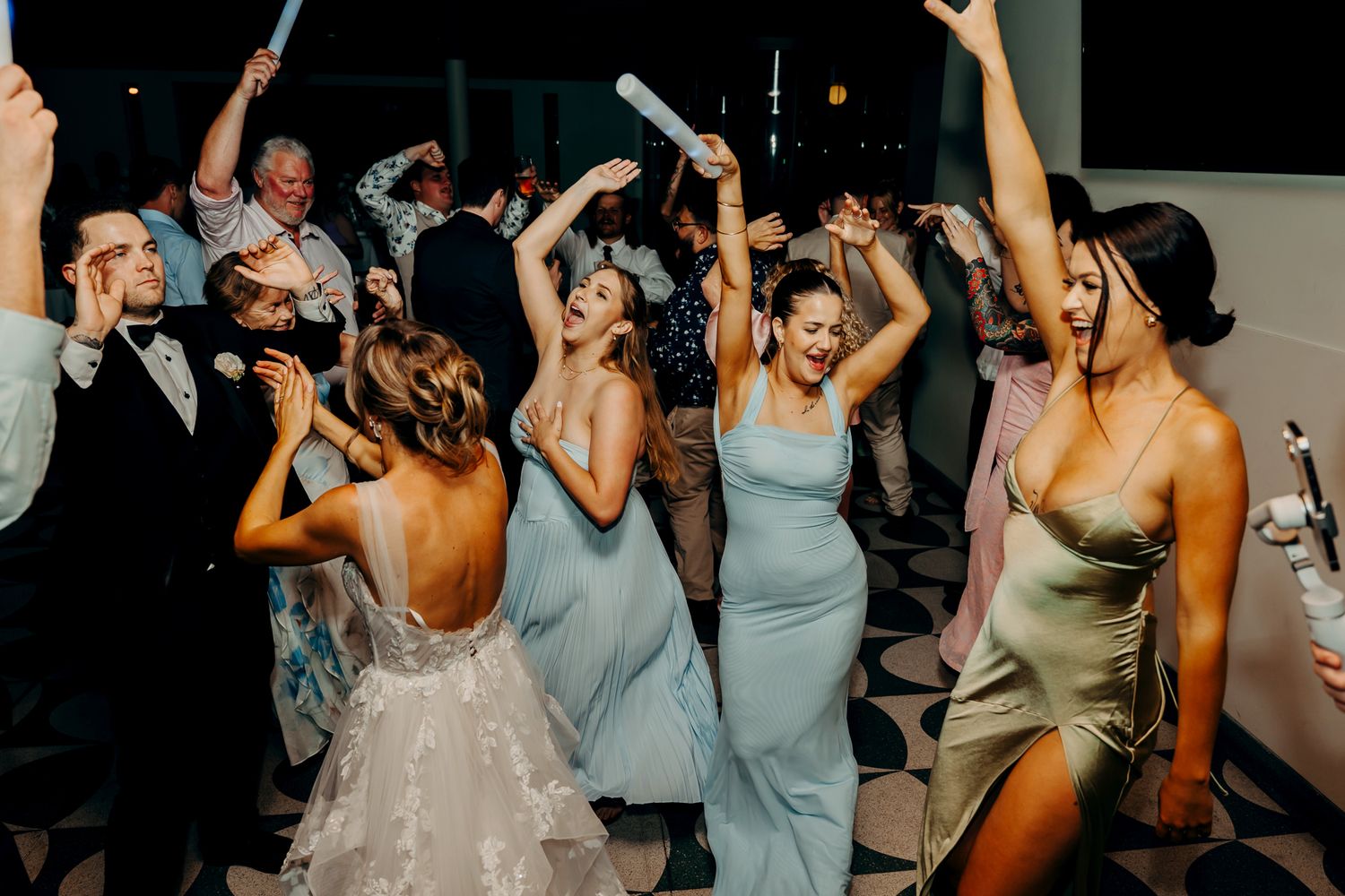 Wedding guests dancing energetically on a dance floor during a reception celebration.