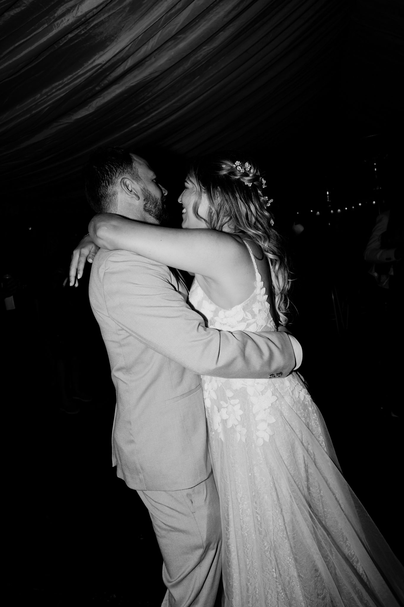A couple shares their first dance in dramatic black and white lighting at their wedding reception.