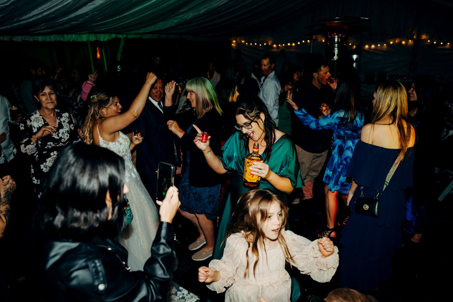 Guests dancing and enjoying themselves at a lively nighttime wedding reception.