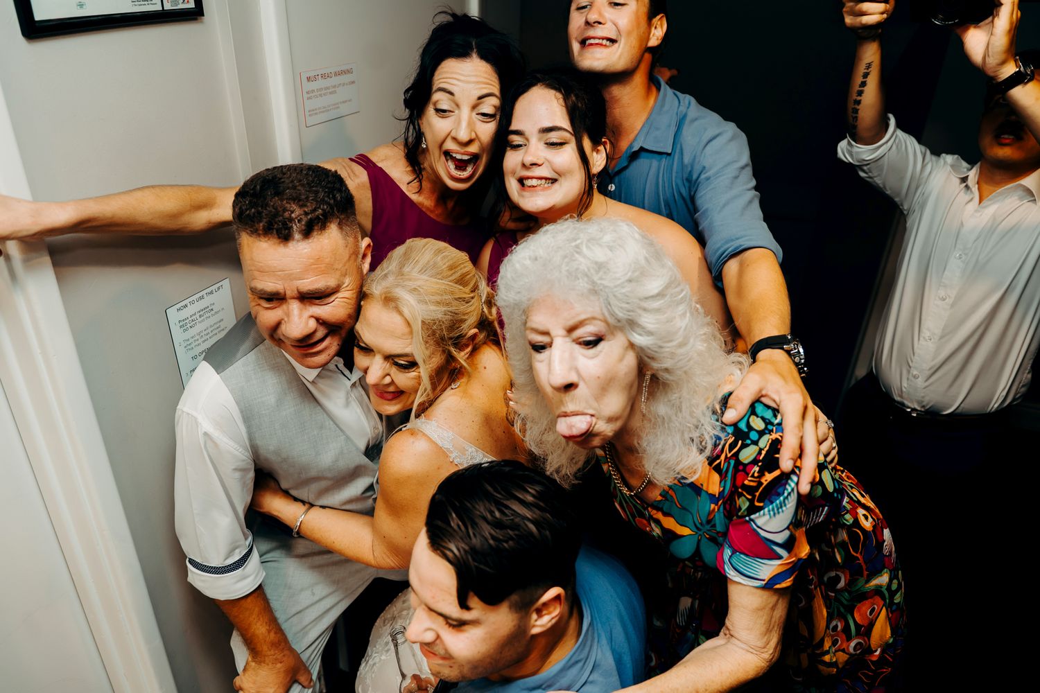 A lively group of friends huddle together laughing and having fun at a party gathering indoors.