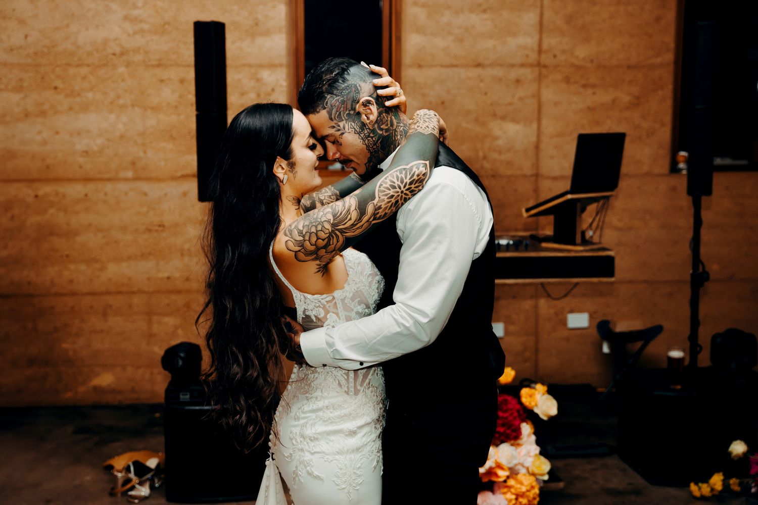 A bride and groom share an intimate dance moment at their wedding reception with wooden paneled walls in the background.
