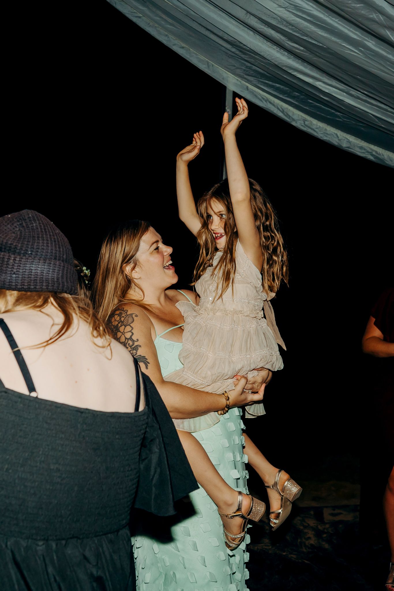 People dancing and celebrating under draped fabric at a dimly lit party venue.