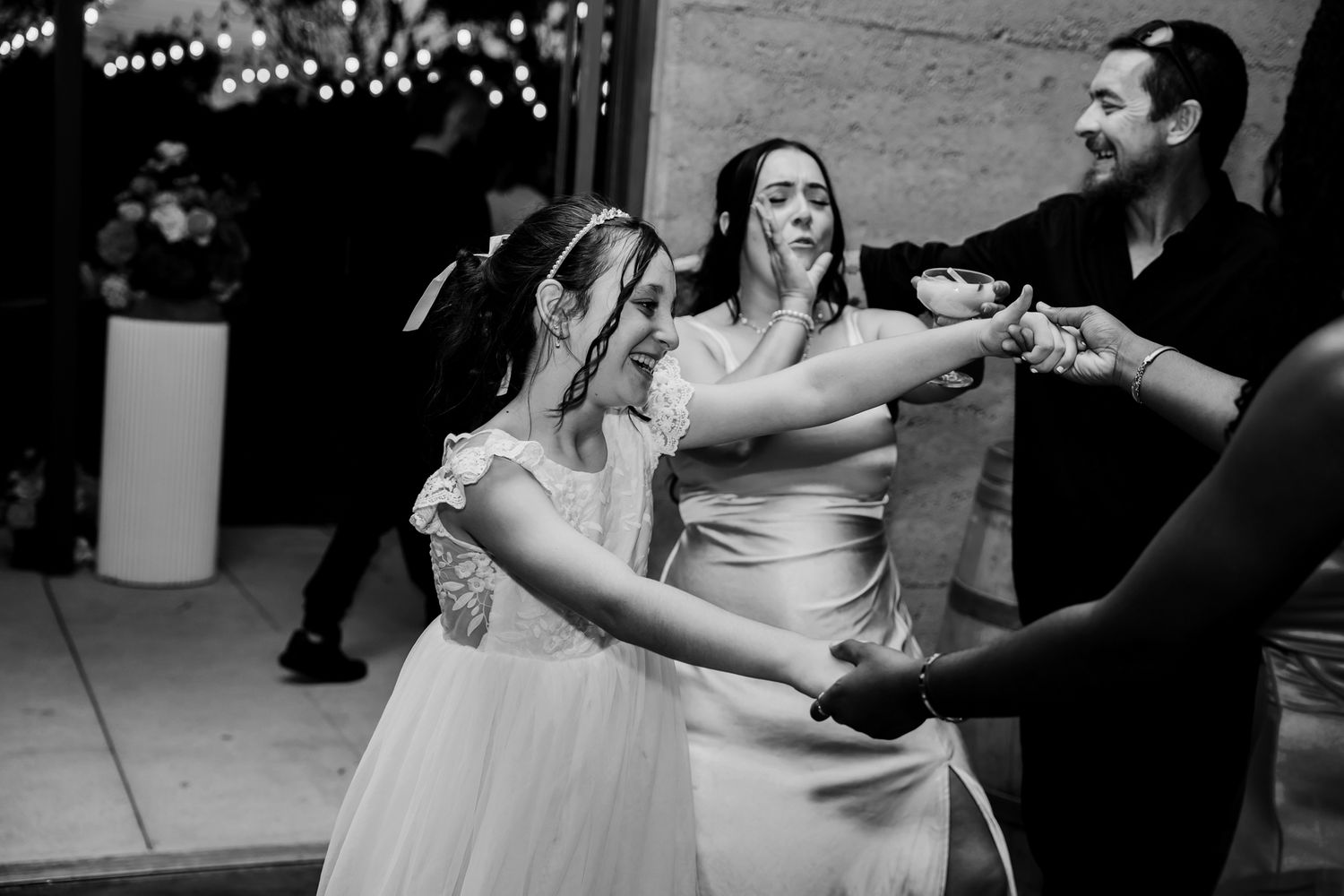 Wedding celebration captured in black and white as people dance together during a lively reception moment.