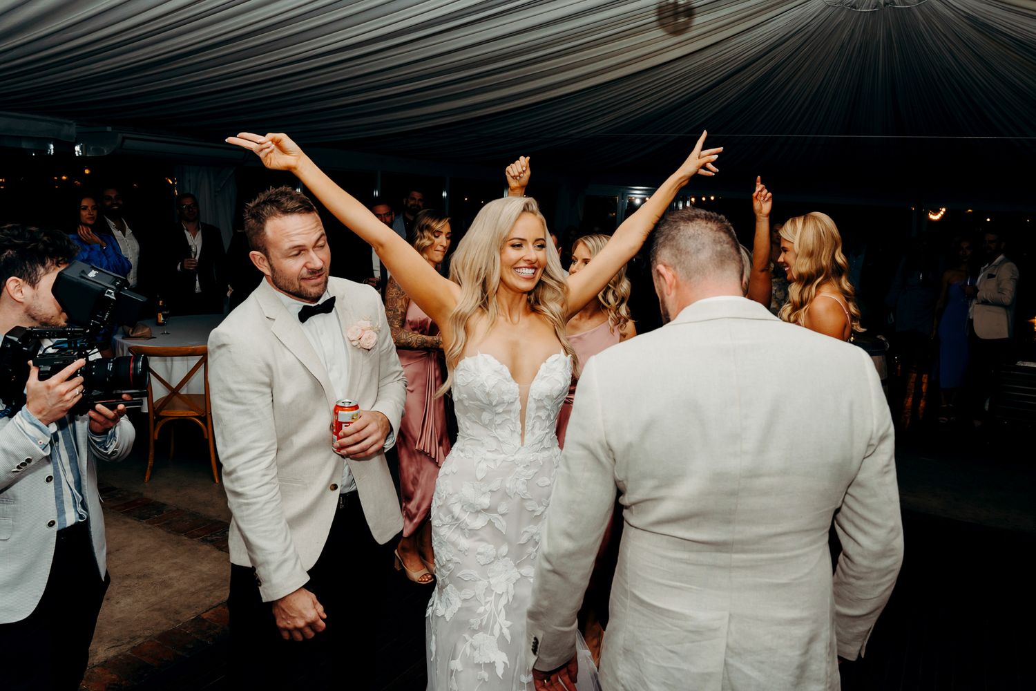Wedding reception celebration under white tent with dancing and festivities.