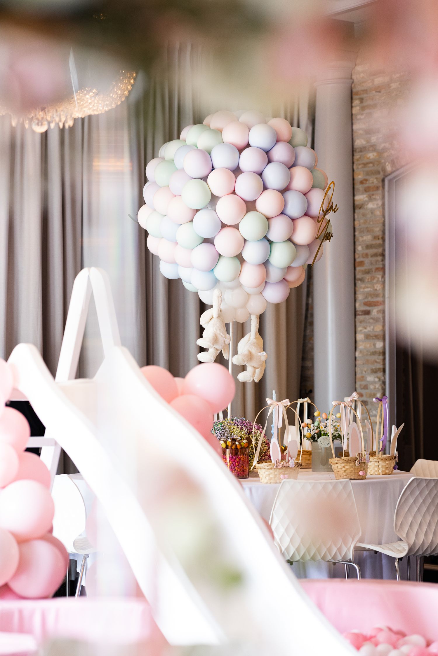 Elegant party decoration with pink and white balloon arrangements and table settings.