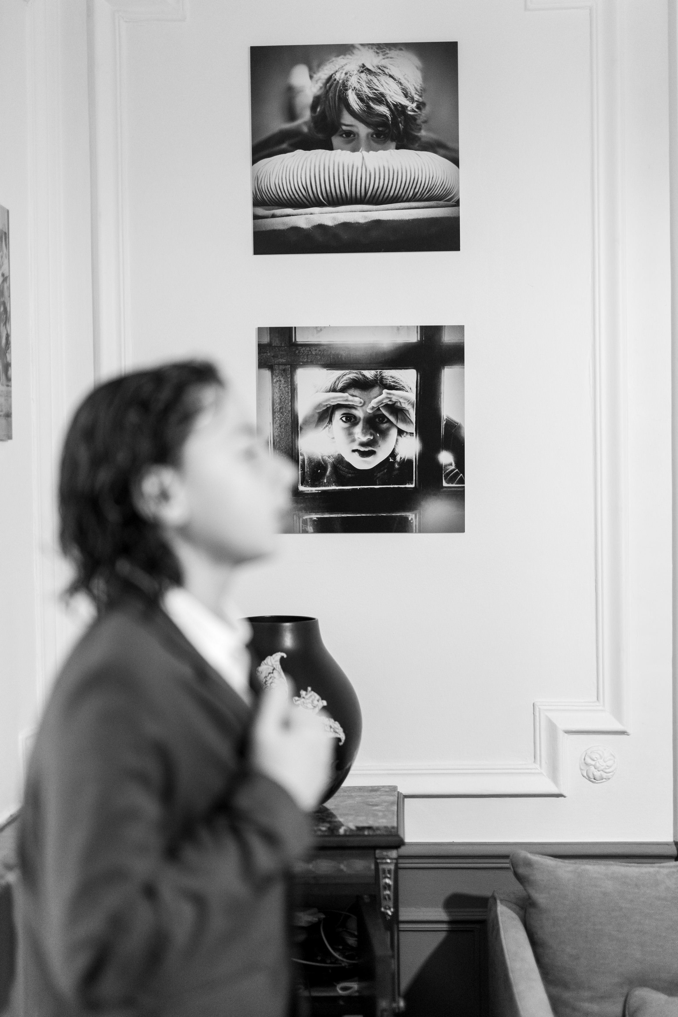 Portrait en noir et blanc d’un homme debout dans une pièce élégante, regard porté vers la lumière.