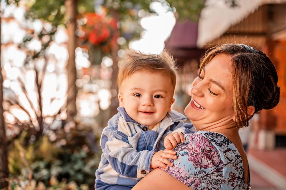 A joyful moment captured outdoors with warm sunset lighting and floral decorations in the background.