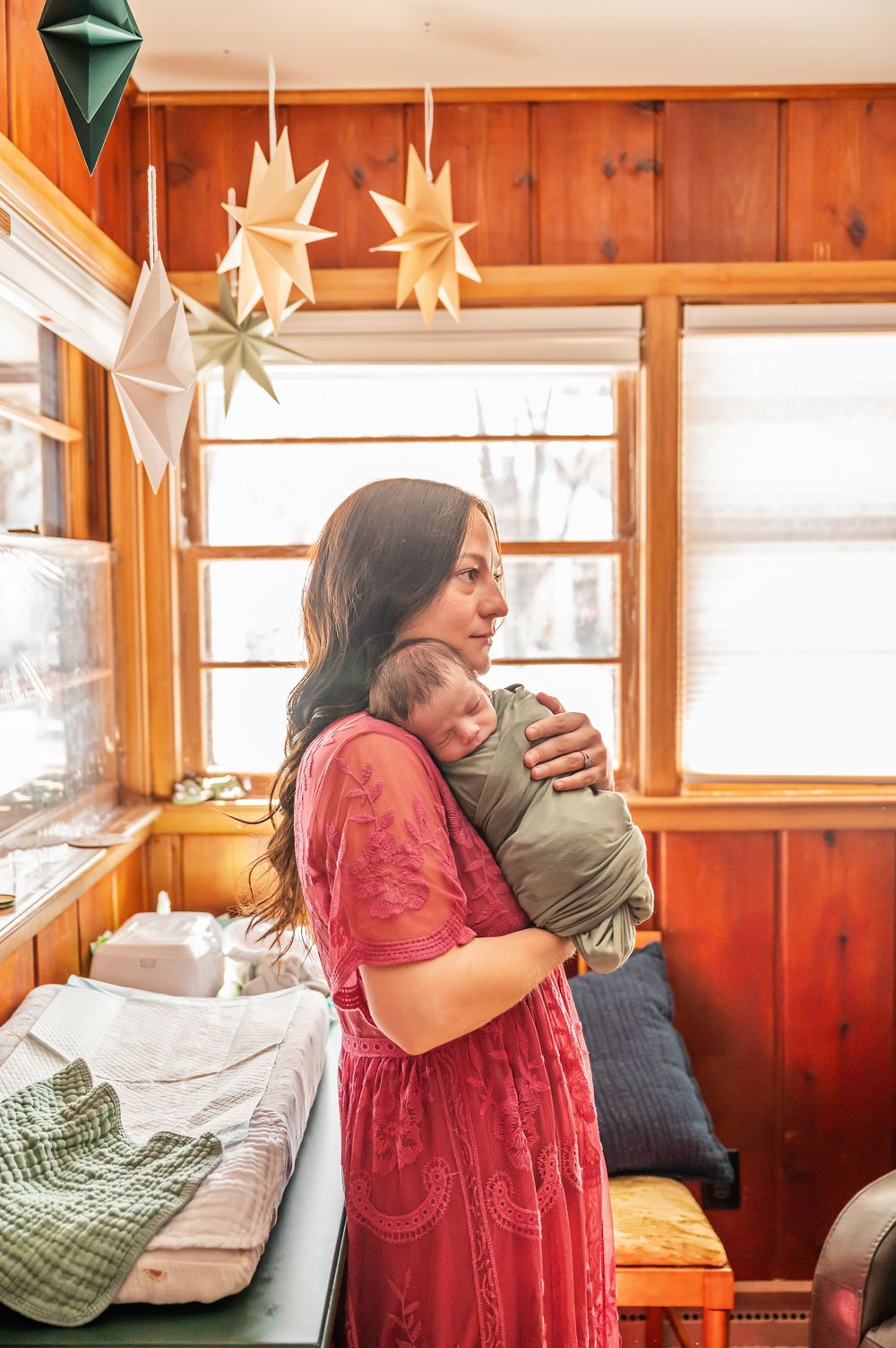 Two people share a warm embrace in a cozy wooden cabin with white star decorations hanging from above.