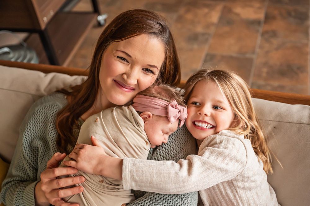 A parent and child share a tender moment while relaxing together on a brown leather couch.