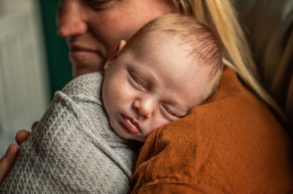 Peaceful moment of a sleeping baby being held in warm, gentle light.