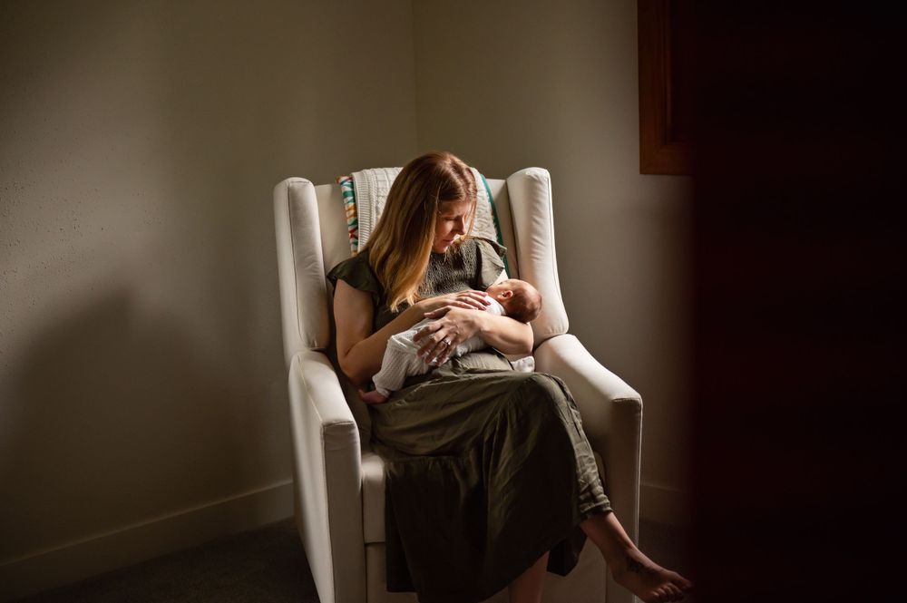 Peaceful moment of parent and baby bonding in white rocking chair with soft lighting.