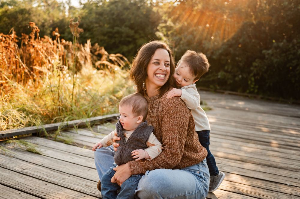 A joyful moment between parent and children on a wooden walkway at sunset.