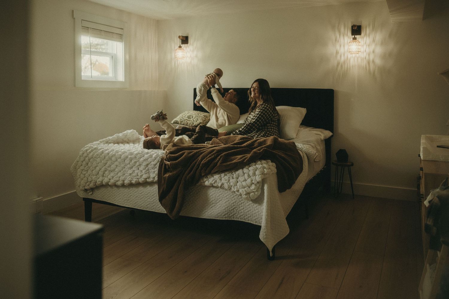A dimly lit interior room with white walls and minimal furniture creates a moody atmosphere.