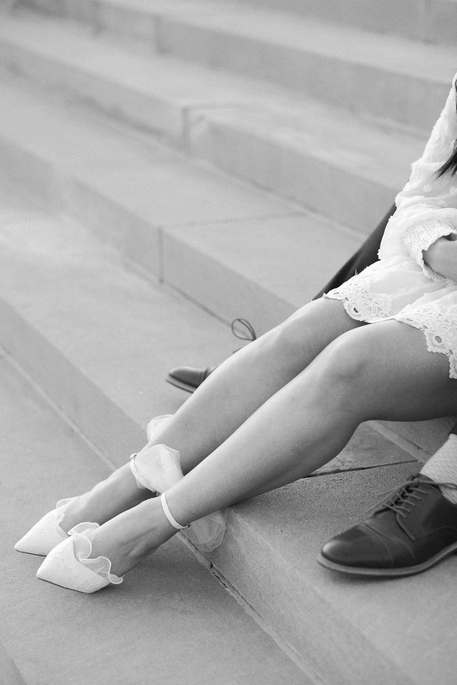 Close-up black and white photo of elegant bridal shoes on stone steps.