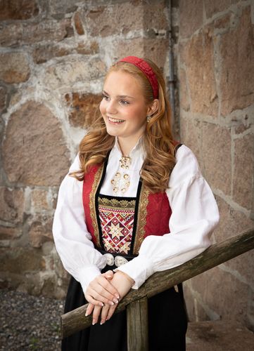 A collection of portraits against a stone wall featuring traditional Nordic folk costume with embroidered details.